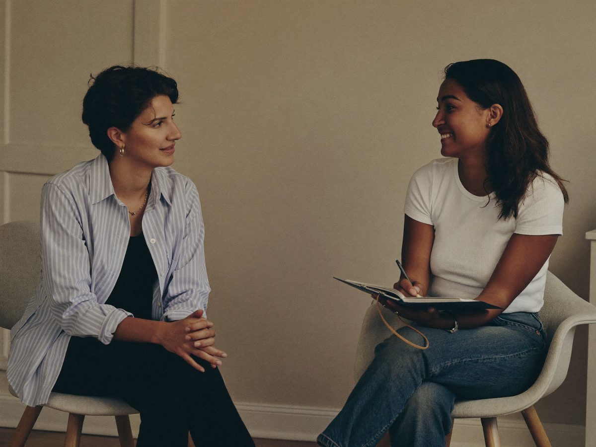 A counselor and a young adult talking warmly in a comfortable home setting.