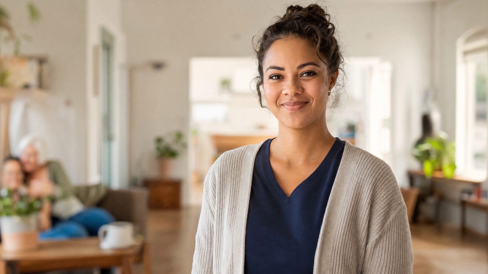 A warm, friendly direct-support professional smiling in a community-care setting.