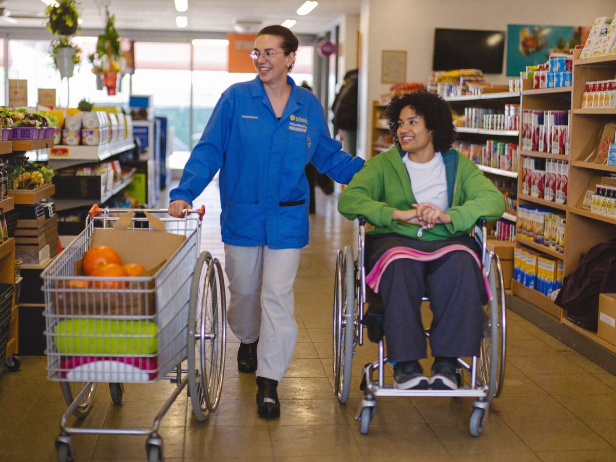 A support worker and an individual shopping together in the community.