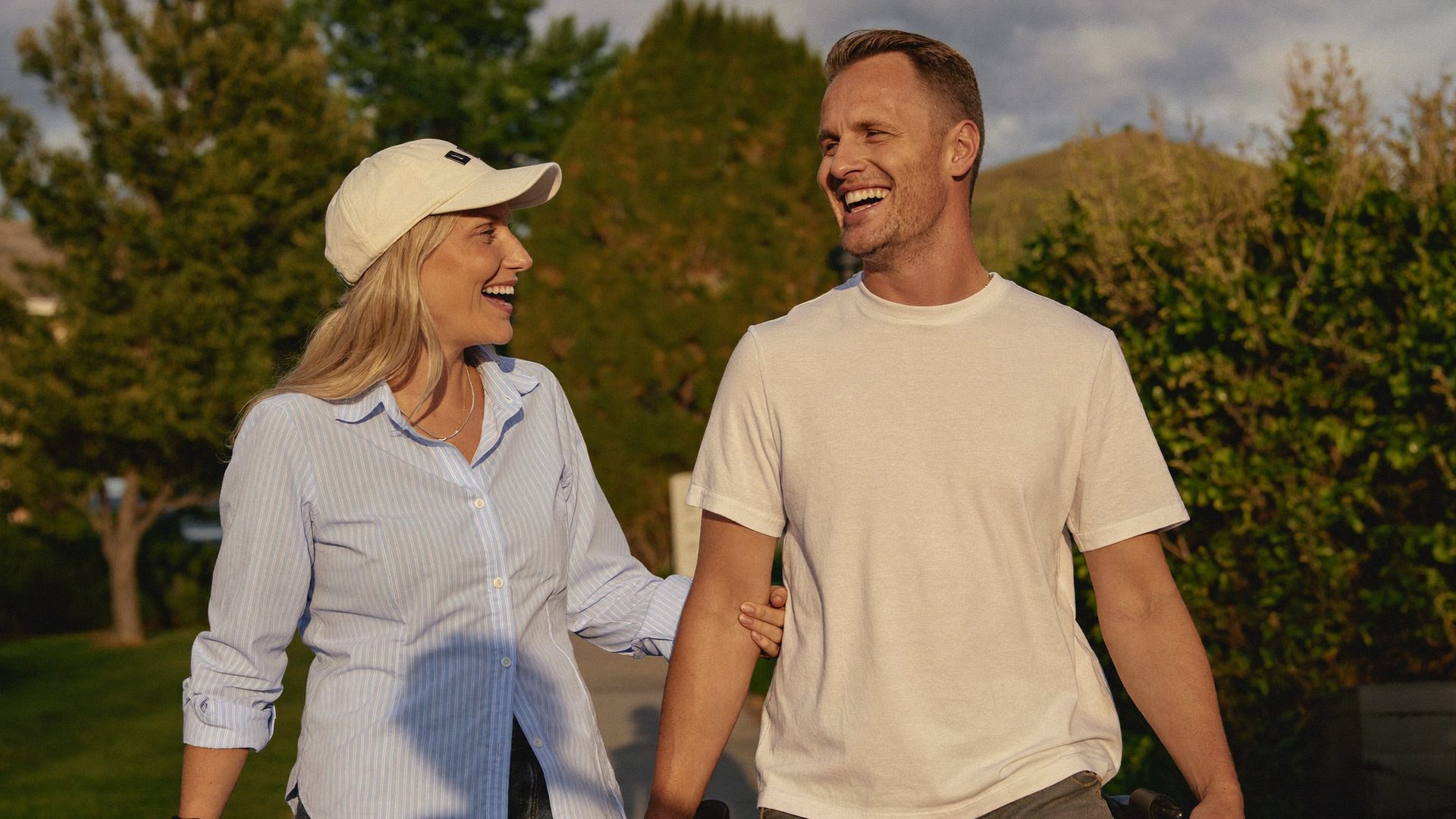 A caregiver walking and laughing beside a young adult in a leafy Pennsylvania neighborhood at golden hour.