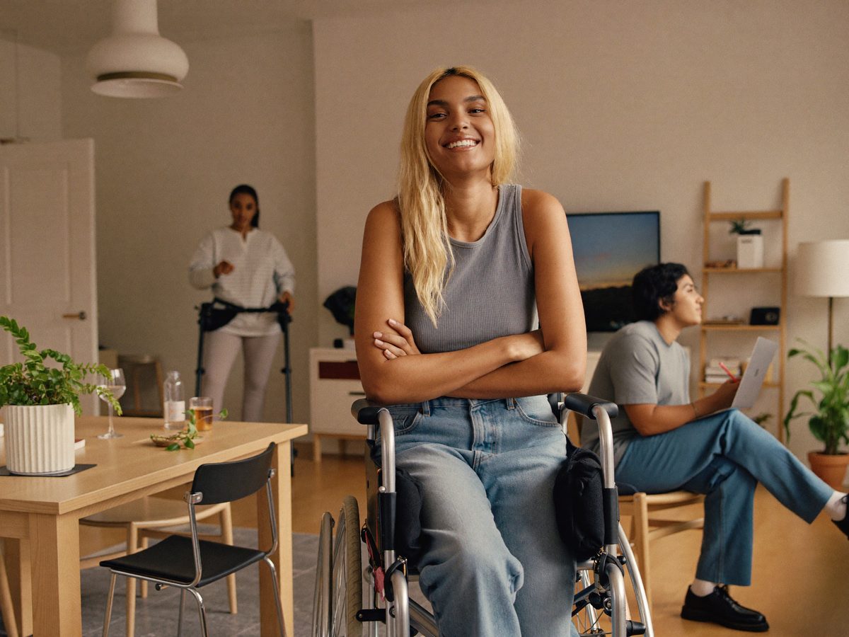 A proud young adult in their own apartment with a support worker nearby.